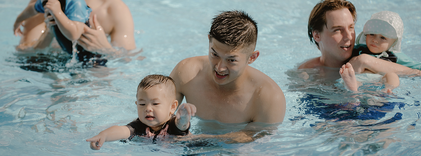 father assisting child to swim