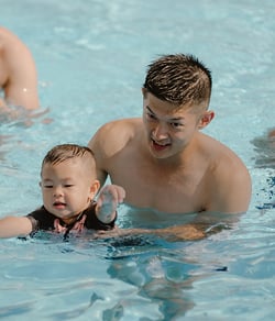 father and child swimming in a pool 